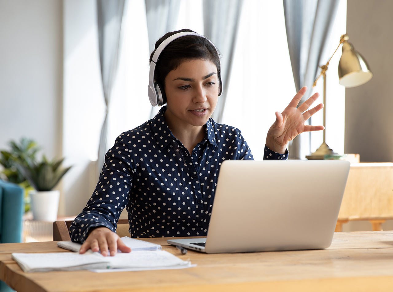 Young female advisor wearing headphones and speaking to her client during a video chat